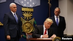 FILE - President Trump signs the original executive order for a U.S. travel ban at the Pentagon in Washington, Jan. 27, 2017.
