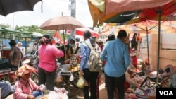 ក្រុមកម្មករ​ចេញ​ពី​រោងចក្រ ទិញ​អាហារ​ថ្ងៃត្រង់​នៅ​ផ្សារ​ក្បែរ​រោងចក្រ។ (ខាន់ សុគុំមនោ/VOA)