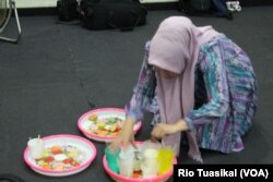 Seorang perempuan nampak merapikan wadah plastik takjil dalam sebuah buka bersama di Bandung, Senin (13/5/2019). (Foto: Rio Tuasikal/VOA)