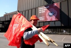 A steelworker carrying flags by German metalworkers' union IG Metall walks past a banner reading "Our future has a heart of steel" during a protest of steelworkers against European policies on April 11, 2016 in Duisburg, western Germany.