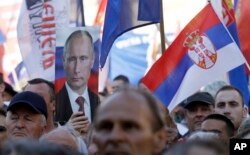 FILE - A Serbian Radical Party supporter holds a picture of Russian President Vladimir Putin during a pre-election rally in Novi Sad, Serbia, April 20, 2016. In a snap election days later, pro-EU Prime Minister Aleksandar Vucic’s party kept its majority.