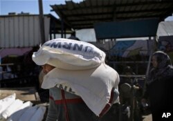 FILE - Palestinians receive food aid at a U.N. warehouse in the Shati refugee camp, Gaza City, Jan. 14, 2018.