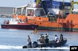 FILE - Migrants stand on the deck of the Aquarius as the ship enters the port of Valencia, June 17, 2018. The migrants began disembarking in Spain after Italy turned the ship away.