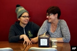 Andrea Ledesma (left) talks with her mother, Cheryl Romanowski, at Classic Slice pizza restaurant, where Ledesma works, in Milwaukee. Ledesma, 28, says her parents owned a house and were raising kids by her age. Not so for her, even though she has a college degree.