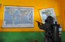 Seorang anggota kepolisian menyemprotkan disinfektan di sebuah sekolah di Palu, Sulawesi Tengah untuk mencegah penyebaran virus corona COVID-19, 20 Maret 2020. (Foto: Muhammad Rifki/AFP)