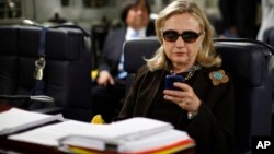 FILE - In this Oct. 18, 2011, file photo, then-secretary of state Hillary Clinton checks her Blackberry from a desk inside a C-17 military plane.