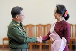 Panglima militer Myanmar Jenderal Min Aung Hlaing (kiri) dan pemimpin partai Liga Nasional untuk Demokrasi (NLD) Aung San Suu Kyi (kanan) berjabat tangan setelah pertemuan mereka, 2 Desember 2015. (Foto: AFP/Phyo Hein Kyaw)