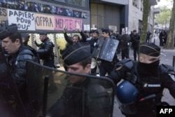 A migrant' supporter raises his hands as a policeman escorts him during a protest against the Jean-Jaurès highschool evacuation in Paris on May 4, 2016.