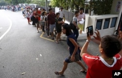 Myanmar nationals queue outside the Myanmar embassy as they wait for polling stations to open for advance voting in Singapore October 17, 2015. About 20000 Myanmar nationals submitted their requests for early voting according to local media.