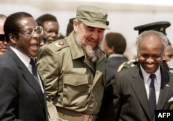 FILE - Cuban President Fidel Castro (C) is, flanked by Zimbabwean President Robert Mugabe (L), as he arrives in Harare, for the 8th non-aligned summit in Zimbabwe, Aug. 31, 1986.
