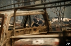 Sheriff's deputies look at a spot that may contain human remains at a home burned in the Camp Fire, Nov. 15, 2018, in Magalia, Calif.