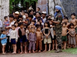 FILE PHOTO: An Indian UN soldier stands guard outside a voting centre in Kompong Cham town, about 100 kilometres northeast of Phnom Penh, as Cambodians watch the polling process on the first day of national elections, Cambodia May 23, 1993.