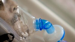 FILE - A man breathes through an oxygen mask at the COVID-19 ICU unit of the Marius Nasta National Pneumology Institute in Bucharest, Romania, Sept. 23, 2021.