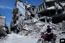 A man rides past destruction in the town of Douma, the site of a suspected chemical weapons attack, near Damascus, Syria, April 16, 2018.