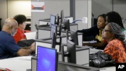 FILE - Job seekers use computers to search for a job at the Texas Workforce Solutions office in Dallas, March 10, 2017.