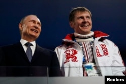 FILE: Russian President Vladimir Putin, left, laughs with Russia's gold medallist bobsleigh athlete, Alexander Zubkov, during the 2014 Sochi Winter Olympics closing ceremony Feb. 23, 2014.