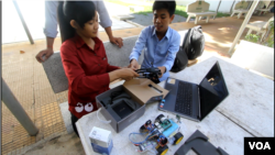 ជាតិ មរកត និងអ៊ឹម ដារ៉ូ រៀបចំសាកល្បងឧបករណ៍រ៉ូបូតបញ្ជាដោយចិត្ត។ (អូន ឆេងប៉រ/VOA)