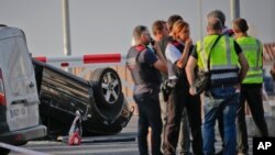 Police officers speak near an overturned car at the spot where terrorists were intercepted by police in Cambrils, Spain, Aug. 18, 2017.