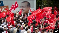 Para pendukung melambai-lambaikan bendera Turki dengan latar belakang gambar Perdana Menteri Recep Tayyip Erdogan saat mereka menunggu kedatangannya di Ankara (9/6).