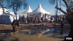 Refugees queue for tea and hot drinks after they arrive near the port on the southern part of Lesbos, Greece, Jan. 23, 2016. (H. Elrasam/VOA)