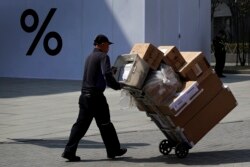 بیجنگ میں ایک مزور درآمدی سامان لے جا رہا ہے۔ فائل فوٹو