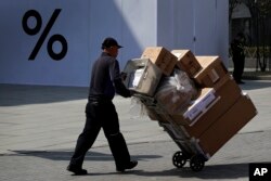 A delivery worker pushes boxes of goods at the capital city's popular shopping mall in Beijing, April 4, 2019. The U.S. and China opened a ninth round of talks Wednesday, aiming to further narrow differences in an ongoing trade war.