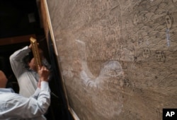 FILE - Staff hang up copies of maps dating from the Qing Dynasty purporting to back up China's claims to vast parts of the South China Sea, in Hong Kong, July. 14, 2016.