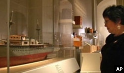The ship model that curator Delphine Hirasuna is examining is one of more than 100 objects featured in the exhibit 'The Art of Gaman.'