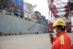 A foreman wearing a face mask works as a cargo ship docks at a container terminal of Qingdao port in Shandong province, China while the country is hit by an outbreak of the new coronavirus, February 4, 2020. cnsphoto via REUTERS