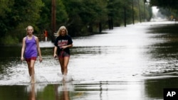 Two women walk along the flooded Parish Barn Road in Iowa, La., Aug. 30, 2017.