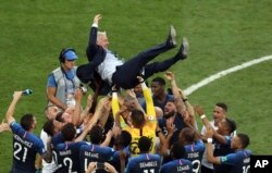 Para pemain Prancis melempar pelatih Prancis Didier Deschamps ke udara saat merayakan akhir pertandingan final antara Prancis dan Kroasia di Piala Dunia 2018 di Stadion Luzhniki di Moskow, Rusia, Minggu, 15 Juli 2018. (Foto: AP/ Thanassis Stavrakis)