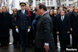 French President Francois Hollande (C) and Paris Mayor Anne Hidalgo attend a ceremony to unveil a commemorative plaque to pay tribute to the victims of the last year's January attacks outside the former offices of French weekly satirical newspaper Charlie Hebdo, Jan. 5, 2016.