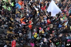 Migrants listen to Mexican authorities as they join a small group of migrants trying to cross the border at the Chaparral crossing in Tijuana, Mexico, Thursday, Nov. 22, 2018.