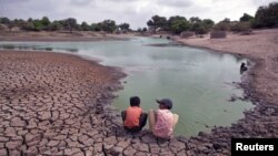 Indian children wash their hands in a partially dried-out natural pond at Badarganj village, in the western state of Gujarat, August 5, 2012.