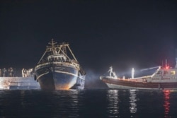 Sebuah kapal nelayan dengan para migran merapat di pelabuhan pulau Lampedusa Sisilia, Italia selatan, Senin malam, 27 September 2021.