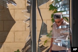 FILE - A Chinese Embassy employee examines broken windows, Aug. 30, 2016, after a suicide bombing in Bishkek, Kyrgyzstan. The bombing highlighted the threat of an ethnic Uighur militant group and the growing Chinese involvement in Syria and Afghanistan to combat it.