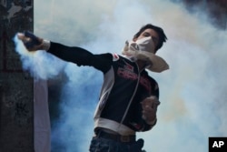 A Kashmiri throws back a tear gas canister at Indian security personnel during a protest after Eid al-Adha prayers in Srinagar, Indian controlled Kashmir, Sept. 13, 2016.