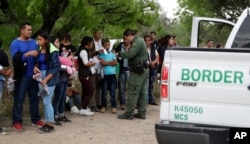 FILE - A U.S. Border Patrol agent checks the names and documents of families who crossed the nearby U.S.-Mexico border, near McAllen, Texas, March 14, 2019.