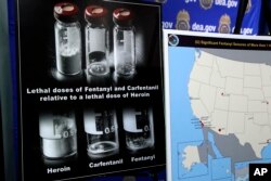 Posters comparing lethal amounts of heroin, fentanyl and carfentanil are on display during a news conference about the dangers of fentanyl at DEA Headquarters in Arlington, Va., June 6, 2017.