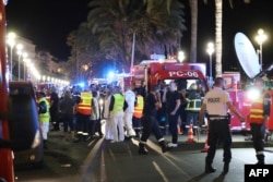 Police officers, firefighters and rescue workers are seen at the site of an attack on July 15, 2016, after a truck drove into a crowd watching a fireworks display in the French Riviera town of Nice.