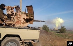 FILE - In this image posted on a militant social media account by the Al-Baraka division of the Islamic State group Feb. 24, 2015, a fighter fires a heavy weapon mounted on the back of a pickup truck during fighting in Tal Tamr, Syria.