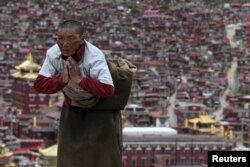 FILE - A Tibetan pilgrim prays near a Buddhist temple in Sertar County of Ganze Tibetan Autonomous Prefecture, Sichuan province, China, July 20, 2015.