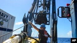 FILE - Tucker Bailey guides a towline through the A-frame while deploying the tow pinger aboard USNS Apache, Oct. 24, 2015. Apache is searching for El Faro’s bridge and voyage data recorder, which became separated from the wreck.