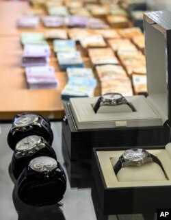 Banknotes and luxury watches are presented, May 3, 2019, at a press conference in Wiesbaden, Germany, about European and American investigators breaking up one of the world’s largest online criminal trafficking operations.