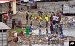 People stand on the shoreline at West Point, Monrovia, Liberia, Aug. 27, 2014.