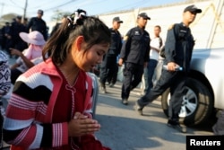 A woman prays while Thai police arrive in front of the gate of Dhammakaya Temple in Pathum Thani province, Thailand, Feb. 16, 2017.