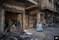 FILE - Shop owner Abu Azar sits outside a destroyed bazaar in the Old City of Mosul, Iraq, Nov. 18, 2017.