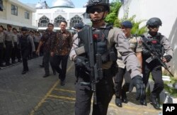 Jakarta Governor Basuki Tjahaja Purnama, popularly known as "Ahok," center, is escorted by anti-terror policemen as he leaves North Jakarta District Court in Jakarta, Indonesia Tuesday, Dec. 20, 2016.