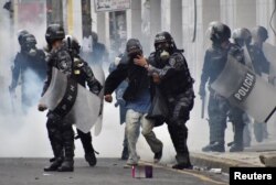 Police help a pedestrian overcome by tear gas as supporters of Salvador Nasralla, presidential candidate for the Opposition Alliance Against the Dictatorship, clash with police during a protest caused by the delayed vote count for the presidential electio