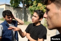 Faisal Grdawe, center, 18, from Syria gestures in front of the National Reception Center For Asylum Seekers in Tirana, Albania, June 6, 2018.